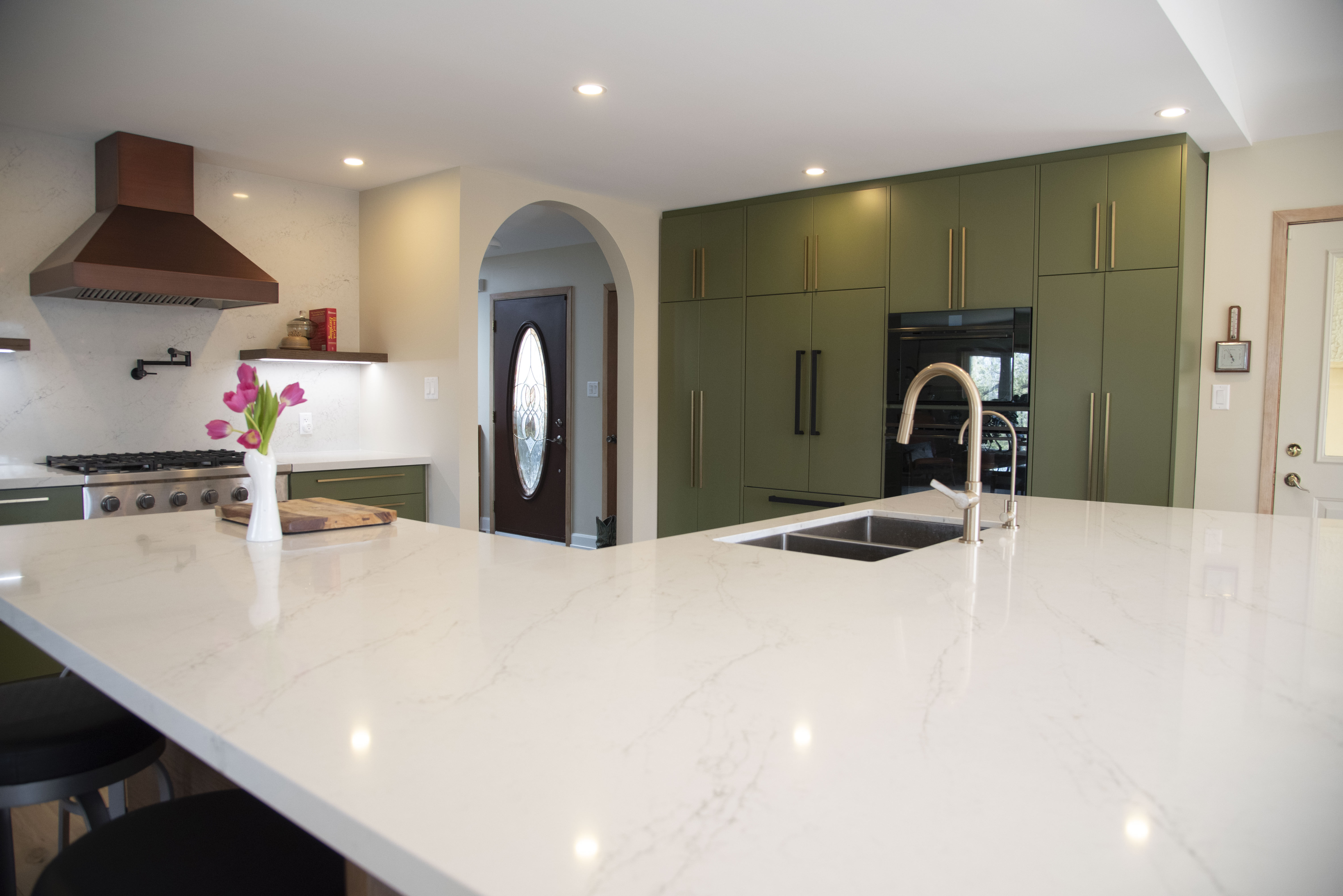Bold green kitchen with marble island and copper hood
